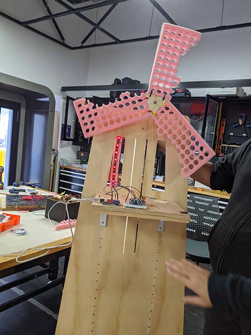 Windmill held by team member above a structure with sensors stuck to upper body height