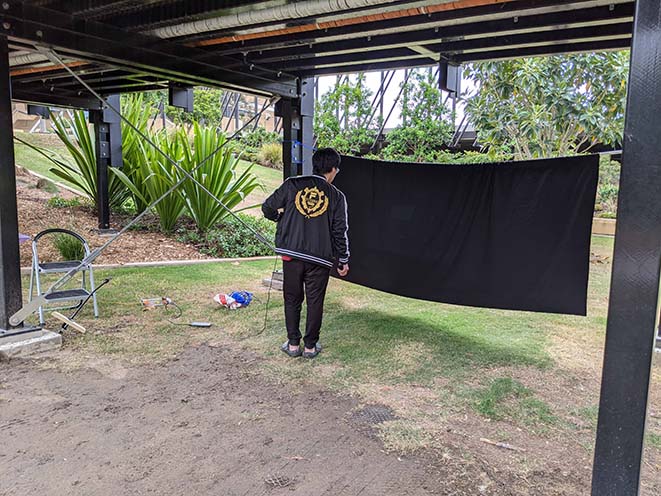 Black fabric suspended between 2 pillars located under the UQ bridge to the Lakes bus station