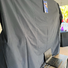 The back of the Galaxy Charter wall at the exhibit, which is draped with a black sheet, with the laptop setup on a small adjacent table